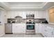 Well-lit kitchen featuring stainless steel appliances, white cabinetry, granite countertops, and a gray subway tile backsplash at 118 Wall St, Redington Shores, FL 33708