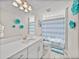 Bright bathroom with a white vanity, modern lighting, and a shower with a blue striped curtain at 12808 Boggy Creek Dr, Riverview, FL 33579