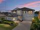 Two-story home with stone accents, a paver driveway, and a two-car garage near a lake at 12808 Boggy Creek Dr, Riverview, FL 33579