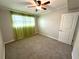Cozy bedroom with neutral carpet, ceiling fan, and a window with green curtains for natural light at 133 15Th Nw St, Largo, FL 33770