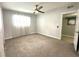 Inviting bedroom with a ceiling fan, soft carpeting, and a view to a door with the text 