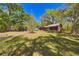 Exterior view of the wood paneled home in a natural setting with large shady trees at 14114 N 301 Hwy, Thonotosassa, FL 33592