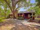 Quaint log cabin with stone chimney, accented by a well-manicured yard and mature trees at 14114 N 301 Hwy, Thonotosassa, FL 33592