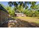 Exterior of the property showcasing the log cabin-style home and shed surrounded by mature trees at 14114 N 301 Hwy, Thonotosassa, FL 33592
