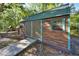Exterior of a shed with double doors, a green corrugated roof, and green trim in a wooded area at 14114 N 301 Hwy, Thonotosassa, FL 33592