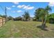 Large backyard featuring a mature shade tree, green grass and a partial view of screened-in lanai at 1542 Picardy Cir, Clearwater, FL 33755