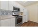 A kitchen showcases white cabinets, stainless steel appliances, and decorative tile backsplash, and warm wood flooring at 17108 Carrington Park Dr # 711, Tampa, FL 33647