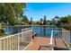 Lakefront view of a wooden dock and bench with metal railings and clear blue water at 3056 Pepperwood W Ln, Clearwater, FL 33761