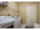 Efficient laundry room features a washing machine, dryer, and sink next to a closed door at 3056 Pepperwood W Ln, Clearwater, FL 33761