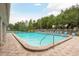 Inviting community pool with lounge chairs on a brick patio, surrounded by lush greenery and a tennis court at 3056 Pepperwood W Ln, Clearwater, FL 33761