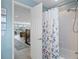 Bright bathroom featuring a shower with floral curtain, tile surround, and a glimpse of the living area at 378 Tennessee Ave, Crystal Beach, FL 34681