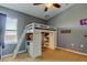Modern bedroom featuring a loft bed, built-in storage, ladder, and ceiling fan at 4250 Warwick Hills Dr, Wesley Chapel, FL 33543