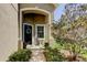 Inviting front entry with a black door and charming wreath, complemented by lush landscaping at 4250 Warwick Hills Dr, Wesley Chapel, FL 33543