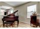 An elegant living room featuring an upright piano and hardwood floors at 4250 Warwick Hills Dr, Wesley Chapel, FL 33543