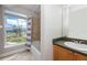 Bright bathroom features a bathtub with shower, vanity sink and large window at 5502 Liberty Plain Cir, Tampa, FL 33611