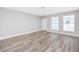 Spacious room with wood flooring, ceiling fan, two windows and a white door at 5502 Liberty Plain Cir, Tampa, FL 33611