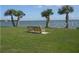 Scenic waterfront view with a bench seat nestled among palm trees on a clear day, offering a peaceful retreat at 585 Sky Harbor Dr # 120, Clearwater, FL 33759