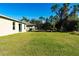 Expansive backyard with a well-maintained lawn, screened lanai, and lush greenery at 6422 Towhlen Rd, North Port, FL 34291
