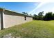 Side yard featuring a grassy lawn and neutral-colored exterior wall at 6422 Towhlen Rd, North Port, FL 34291