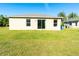 Backyard view showing the exterior with sliding glass door and grass lawn at 6422 Towhlen Rd, North Port, FL 34291