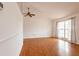 Bright living room with hardwood floors, white walls, a ceiling fan, and large windows offering natural light at 7934 Aden Loop, New Port Richey, FL 34655
