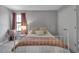 Cozy bedroom features a metal bed frame, neutral bedding and mauve colored curtains and linens at 9133 Warm Springs Cir, Parrish, FL 34219