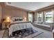 Spacious bedroom with a large bed, tray ceiling, windows and seating area at 9133 Warm Springs Cir, Parrish, FL 34219