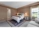 Stylish bedroom with large rug, paneled accent wall, sofa and white bedding at 9133 Warm Springs Cir, Parrish, FL 34219