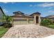 A two-story home with a three-car garage, stone accents, and a paver driveway at 9133 Warm Springs Cir, Parrish, FL 34219