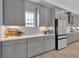 This kitchen boasts sleek grey cabinets, quartz countertops, a white backsplash, and stainless steel appliances at 9133 Warm Springs Cir, Parrish, FL 34219