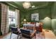 Well-decorated office with green walls, a leather couch, designer chandelier, and natural light at 9133 Warm Springs Cir, Parrish, FL 34219