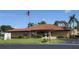 A well-maintained building with a red tile roof and lush landscaping under a sunny sky with an American flag at 9208 37Th N St, Pinellas Park, FL 33782