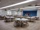 Spacious meeting room is furnished with round tables, chairs, stage, American flag, and light vinyl floors at 9208 37Th N St, Pinellas Park, FL 33782