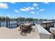 Waterfront dock featuring an outdoor dining set, boat lifts, and scenic views of the water and distant waterfront homes at 10905 Elliot St, Riverview, FL 33578