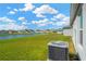 Scenic backyard view featuring a serene pond and lush green lawn with a modern air conditioning unit at 11221 Gold Compass St, Gibsonton, FL 33534
