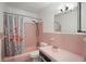 Pink tiled bathroom featuring a tub with flamingo shower curtain, toilet, and sink at 121 46Th Ave # 2H, St Pete Beach, FL 33706