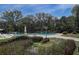 This pool is surrounded by mature trees, bushes, white furniture and decorative lampposts at 1500 Sunset Rd # G4, Tarpon Springs, FL 34689