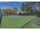 A full tennis court surrounded by trees on a partly cloudy day at 1500 Sunset Rd # G4, Tarpon Springs, FL 34689