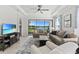 Bright living room with tray ceiling, modern decor, and serene lake views through a large glass window at 15635 Sacile Ln, Bradenton, FL 34211