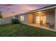 Home backyard has covered porch with seating and sliding door, as well as lush lawn at 18184 Turning Leaf Cir, Land O Lakes, FL 34638