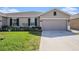 Single-Gathering home with gray stucco, concrete driveway, an attached garage, and landscaped yard at 18184 Turning Leaf Cir, Land O Lakes, FL 34638