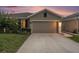 Single-Gathering home with gray stucco, concrete driveway, an attached garage, and landscaped yard at 18184 Turning Leaf Cir, Land O Lakes, FL 34638
