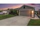 Single-Gathering home with gray stucco, concrete driveway, an attached garage, and landscaped yard at 18184 Turning Leaf Cir, Land O Lakes, FL 34638