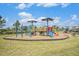 Colorful playground equipment on woodchip base, bordered by green grass, offering a safe and fun play area at 18184 Turning Leaf Cir, Land O Lakes, FL 34638