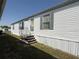 Charming mobile home featuring white siding, blue shutters, and a welcoming front entrance at 215 S Port Royal Ln, Apollo Beach, FL 33572