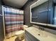 This bathroom features a shower with a multicolored curtain and a dark gray vanity with a white sink at 21838 Edgewater Dr, Port Charlotte, FL 33952