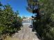 View down a wooden dock surrounded by lush greenery, with a house in the distance at 21838 Edgewater Dr, Port Charlotte, FL 33952