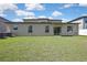 Expansive backyard featuring lush green grass and a neutral-colored exterior with sliding glass doors at 35965 Saddle Palm Way, Zephyrhills, FL 33541
