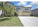 Two-story home with a three-car garage, stucco exterior, lawn, and well-maintained landscaping at 35965 Saddle Palm Way, Zephyrhills, FL 33541
