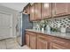 This kitchen features granite countertops, mosaic tile backsplash, stainless steel appliances and wood cabinetry at 35965 Saddle Palm Way, Zephyrhills, FL 33541